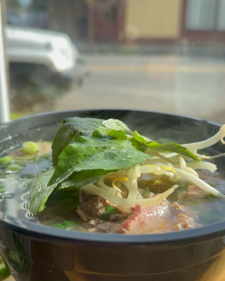 Classic beef phở with steaming broth and fresh basil at La Cà Café